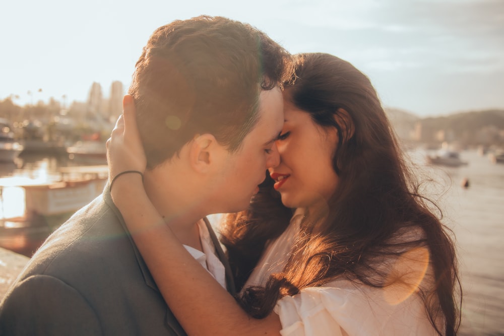 man and woman kissing beside bay