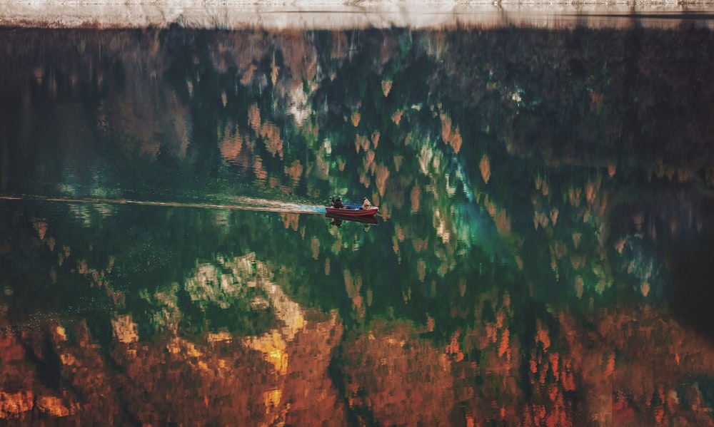 a boat floating on top of a lake next to a forest