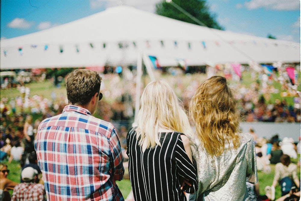 three person's standing front of field