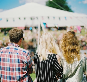 three person's standing front of field