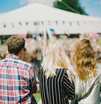 three person's standing front of field