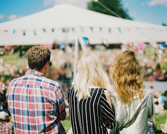 three person's standing front of field