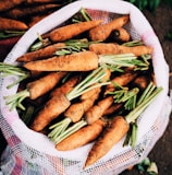 ripe carrots inside white net sack