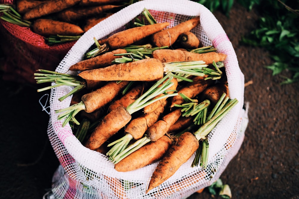 carottes mûres à l’intérieur d’un sac en filet blanc