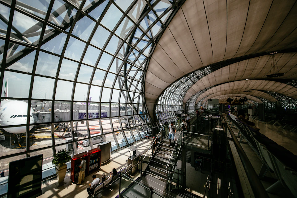 Large modern airport terminal with curved glass ceiling and natural light pouring in