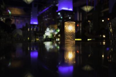 Dimly lit cafe interior with flickering candles casting eerie shadows on deep purple walls.