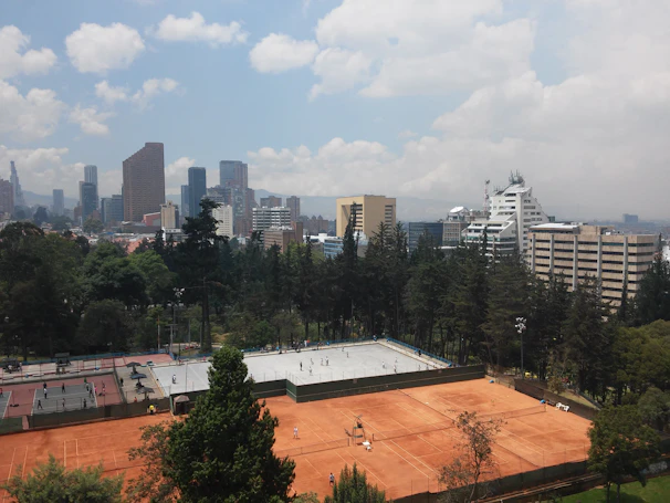 A panoramic view of the tennis courts with the Eiffel Tower faintly visible in the background.