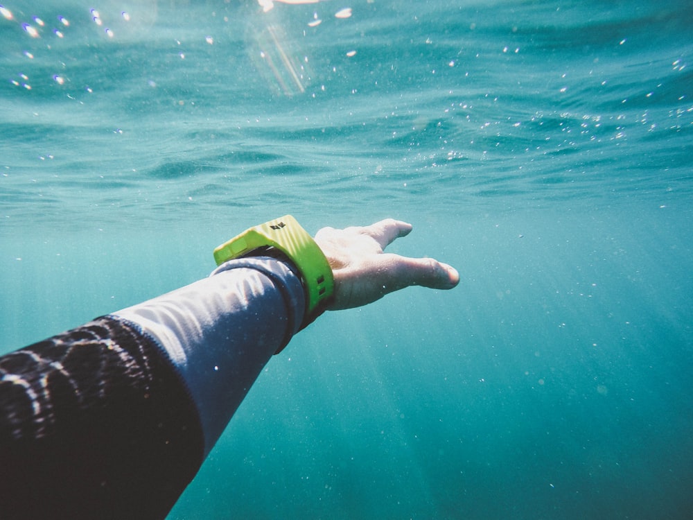 La mano de una persona que se extiende bajo el agua.