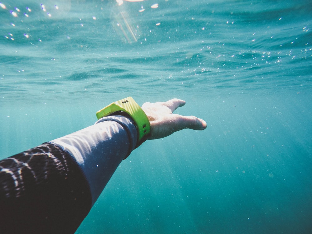 A person's hand reaching out underwater.