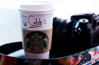 Close-up of a hand holding a personalized paper cup with vibrant branding.