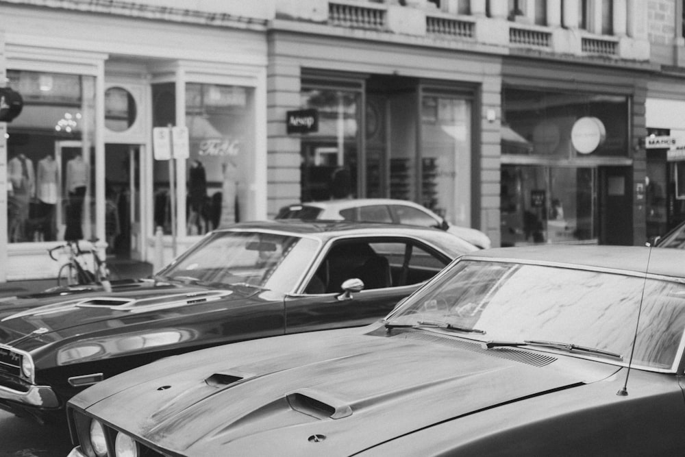 greyscale photography of cars on road beside buildings