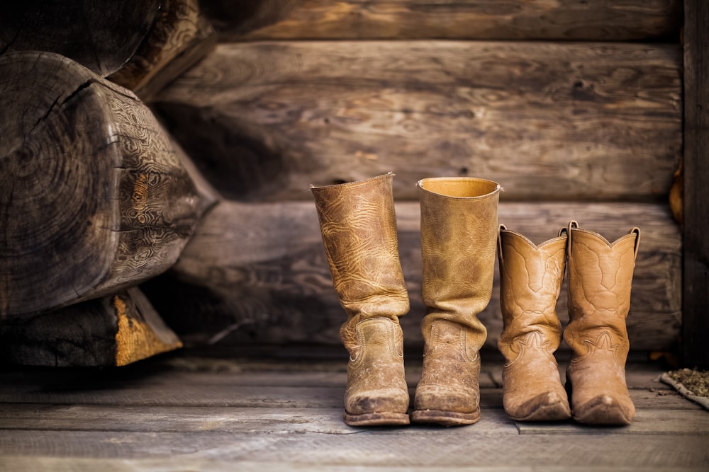 deux paires de bottes de cowboy en cuir marron près de la bûche marron