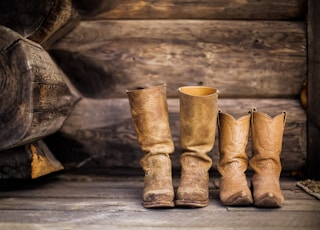 two pair of brown leather cowboy boots near brown log