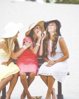 three women sitting on brown wooden bench