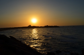 A serene sunset over Cádiz's coastline with golden light reflecting on the calm sea.