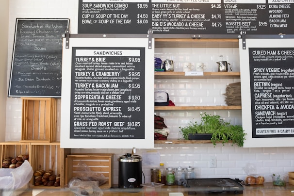 Close-up of a QR code menu printed on a small tabletop stand, with sandwiches visible in the background.