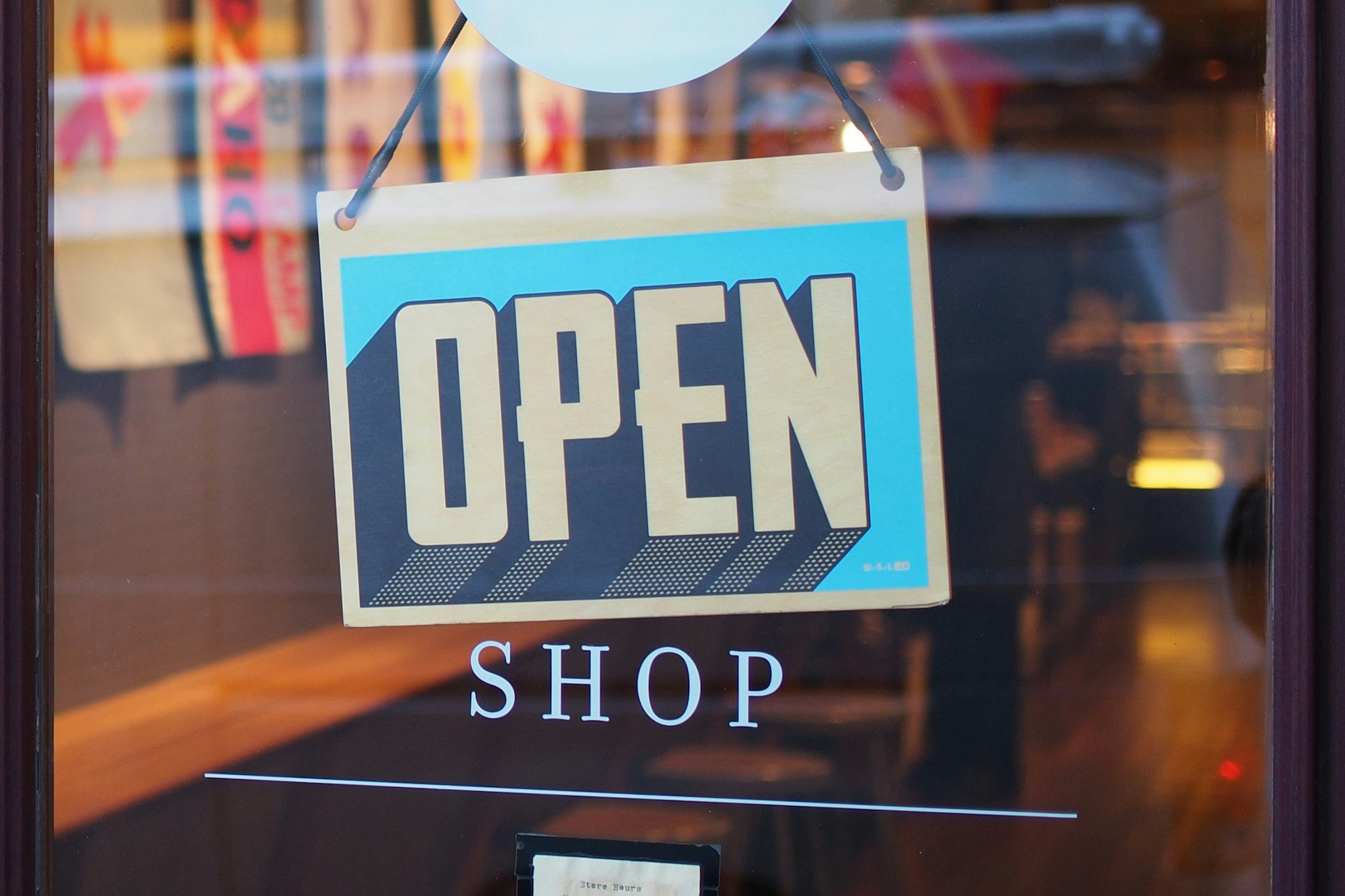 An "Open" sign on a glass door of a shopping business