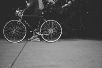 grayscale photo of person holding a bicycle