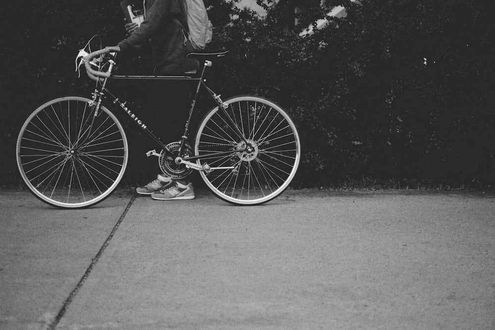 Black and white shot of bikes on sidewalk with owner in New Balance trainers and backpack