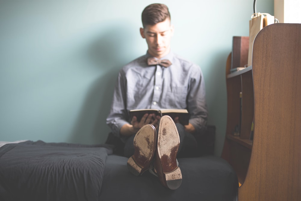 man wearing gray dress shirt reading book