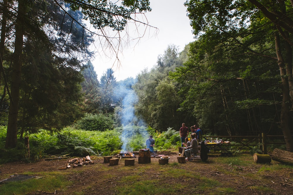 a group of people standing around a fire in the woods