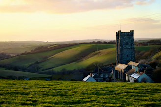 A peaceful rural landscape in Palencia at sunset with rolling hills and a historic church in the background
