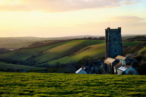 A peaceful rural landscape in Palencia at sunset with rolling hills and a historic church in the background
