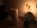 A dimly lit kitchen counter with a roll of paper towels, a blue appliance, and a plug-in night light featuring a chef figurine holding a pizza.