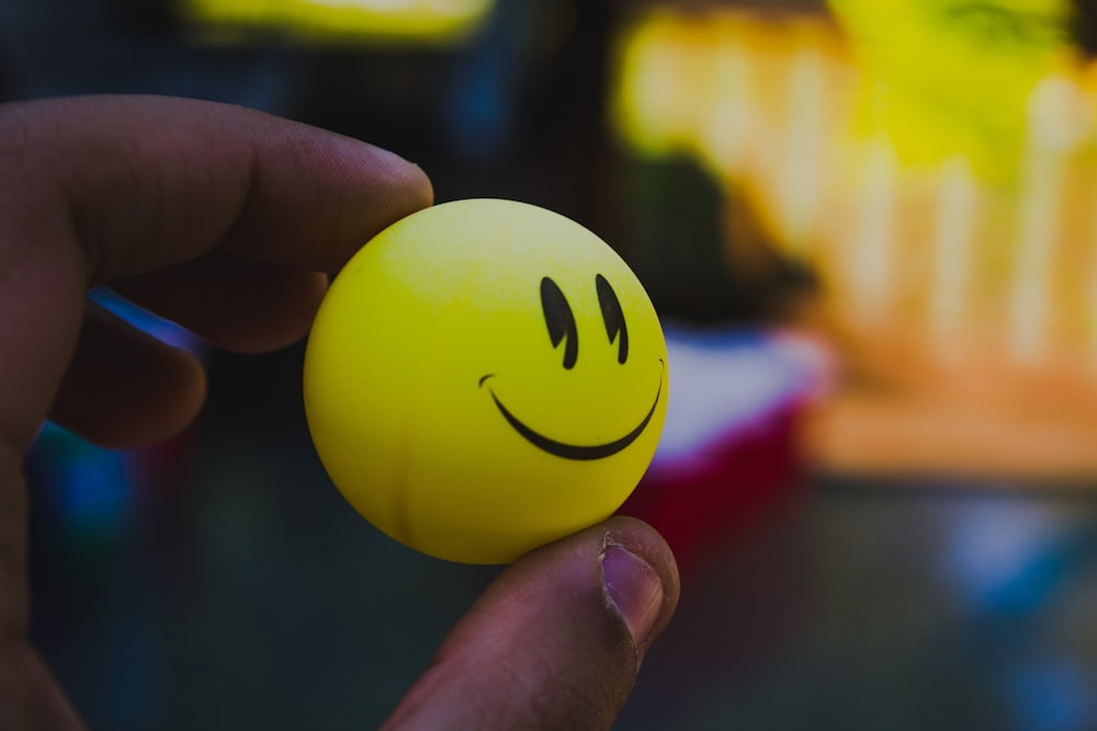 pessoa segurando bola de emoji amarelo