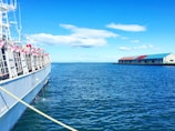 A wide shot of a ship docked at harbor under a clear blue sky, reflecting readiness and promise