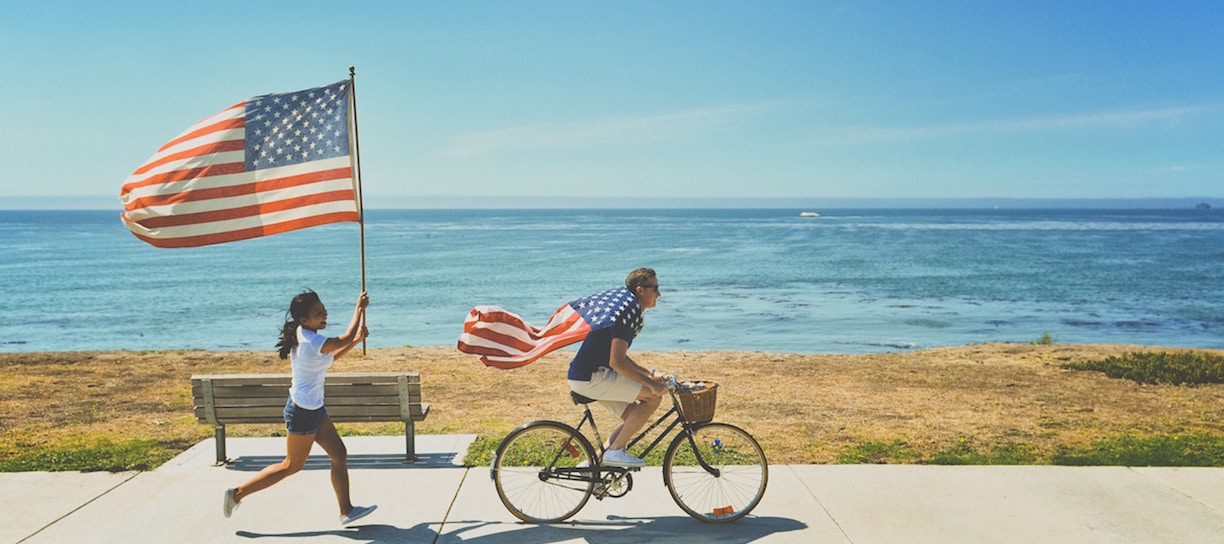 man riding bike and woman running holding flag of USA