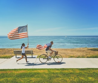 man riding bike and woman running holding flag of USA