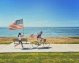 man riding bike and woman running holding flag of USA