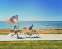 man riding bike and woman running holding flag of USA