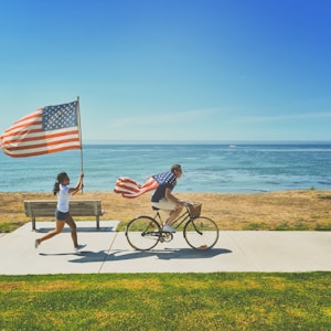 man riding bike and woman running holding flag of USA