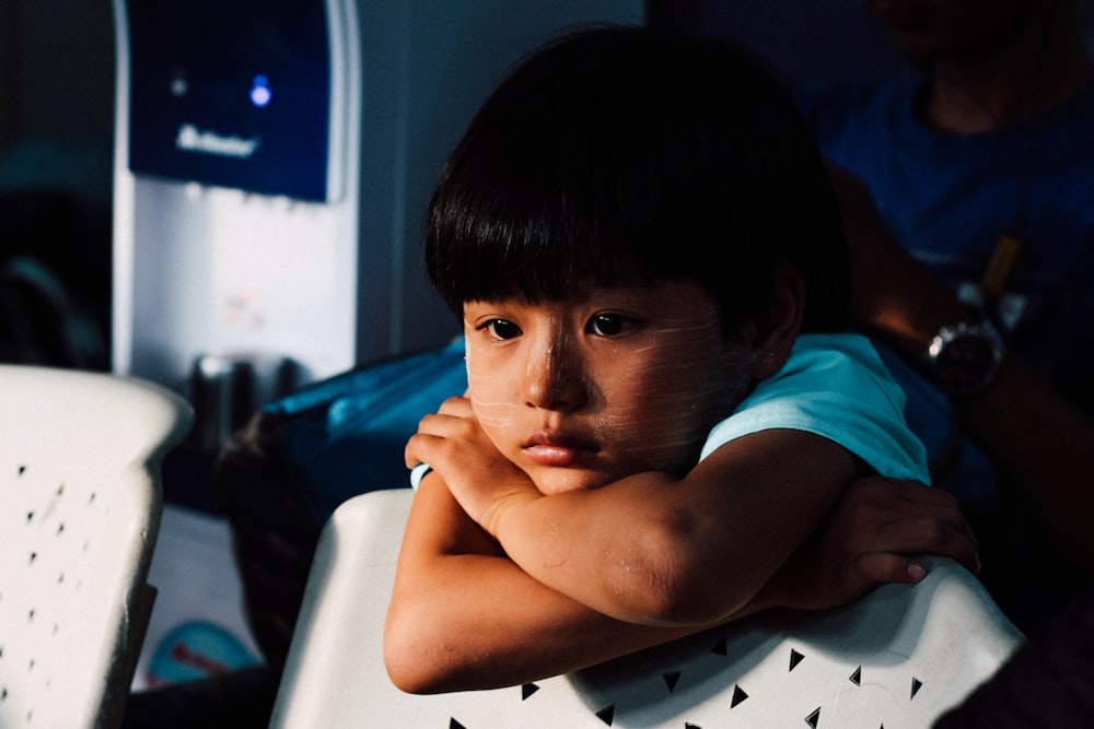 boy leaning on white chair