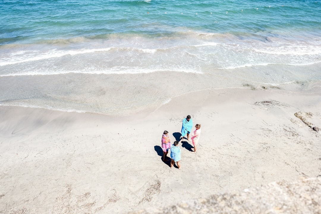 four people standing on seashore