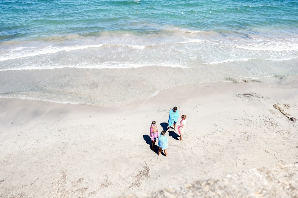 four people standing on seashore