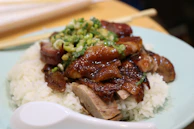 An elegant plate of duck breast with a ginger-soy reduction, accompanied by steamed jasmine rice.