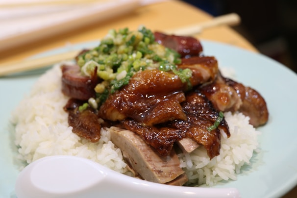 A beautifully plated dish of roast duck rice with fresh herbs and vibrant vegetables.