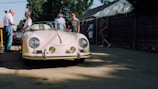 Members gathered around a classic car at a sunny outdoor meet.