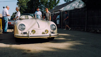 A classic vintage car gathering on a sunny day with smiling owners chatting.