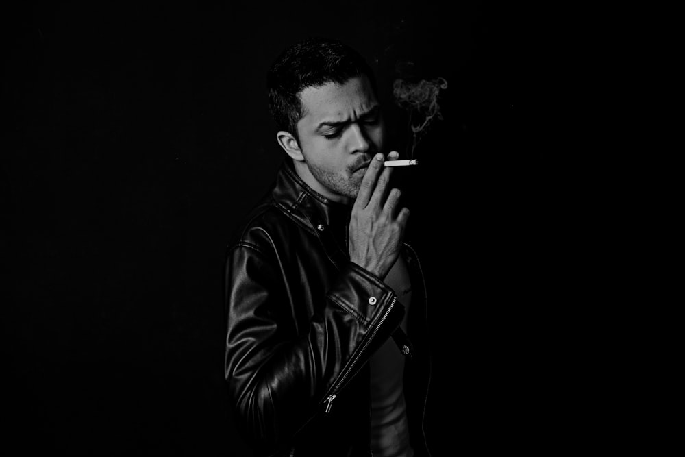 grayscale photo of man smoking cigarette
