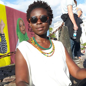 A stylish woman wearing layered necklaces in a sunlit urban setting.