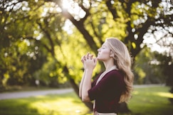 woman praying under tree during daytime