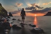 man standing on stone looking at sunset