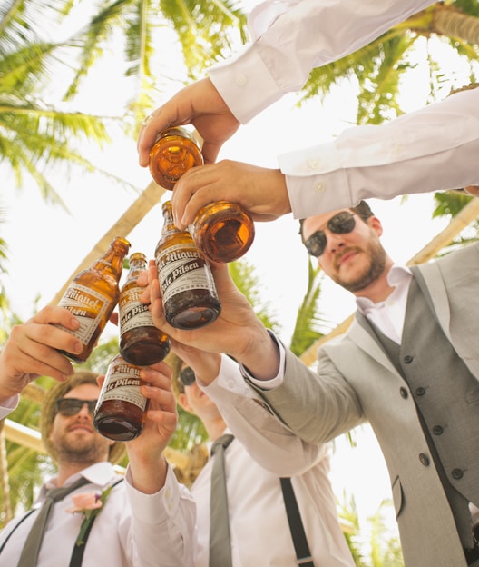 low angle of men holding beer bottles and having a toast