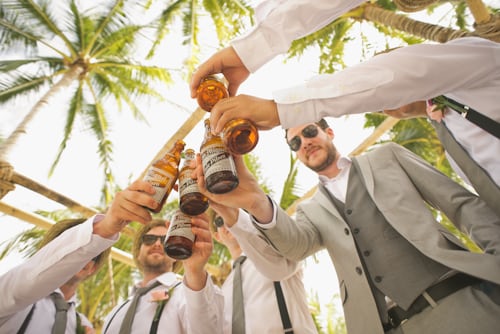 Lo sposo e i suoi testimoni brindano con bottiglie di birra per la foto di matrimonio su Instagram dei loro amici. 