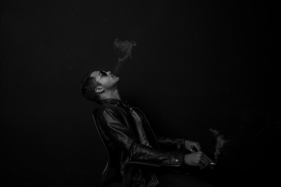 grayscale photo of man with cigarette stick