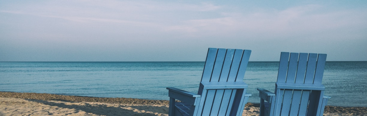 two blue beach chairs near body of water